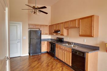 A kitchen with wooden cabinets and a black refrigerator.